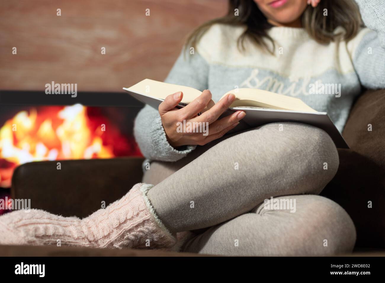 Nahaufnahme einer Frau, die in der Wärme ihres Hauses ein Buch liest. Stockfoto