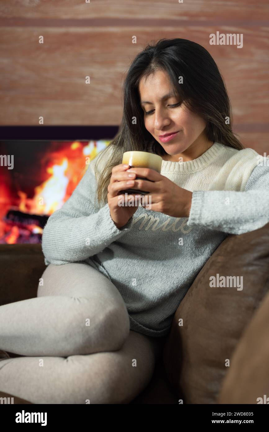 Frau genießt einen Drink, während sie sich zu Hause entspannt. Stockfoto