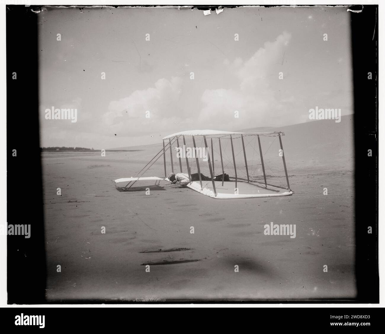 Geschichte der Luftfahrt - Wright Brothers - Wilbur Wright in Bauchlage auf dem Segelflugzeug kurz nach der Landung, seine Rutschspuren sind hinter ihm sichtbar und im Vordergrund die Rutschspuren einer früheren Landung - Kitty Hawk, North Carolina Stockfoto