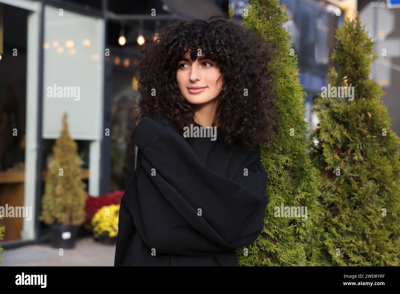 Glückliche junge Frau im stylischen schwarzen Pullover draußen Stockfoto