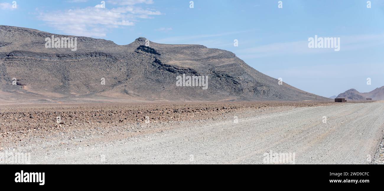 Landschaft mit Schotterstraße und Sandsteinhügeln des Losberg-Gebirges, aufgenommen im hellen Licht des späten Frühlings in der Wüste Naukluft, Namibia, Afrika Stockfoto