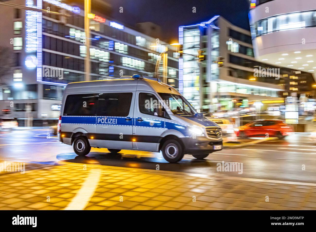 Innerstädtische Straße mit Fahrzeugen, moderne Architektur am Abend. Bewegungsunschärfe. Polizeiauto. // 17.01.2024: Stuttgart, Baden-Württemberg, Deutschland. *** Innenstadtstraße mit Fahrzeugen, moderne Architektur am Abend Motion Blur Polizeiauto 17 01 2024 Stuttgart, Baden Württemberg, Deutschland Stockfoto