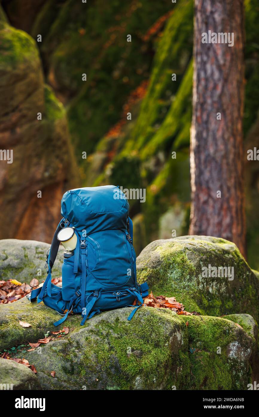 Rucksack mit Reisebecher auf Felsen im Wald. Wander- und Trekkingausrüstung. Essentials für Outdoor-Sport Stockfoto