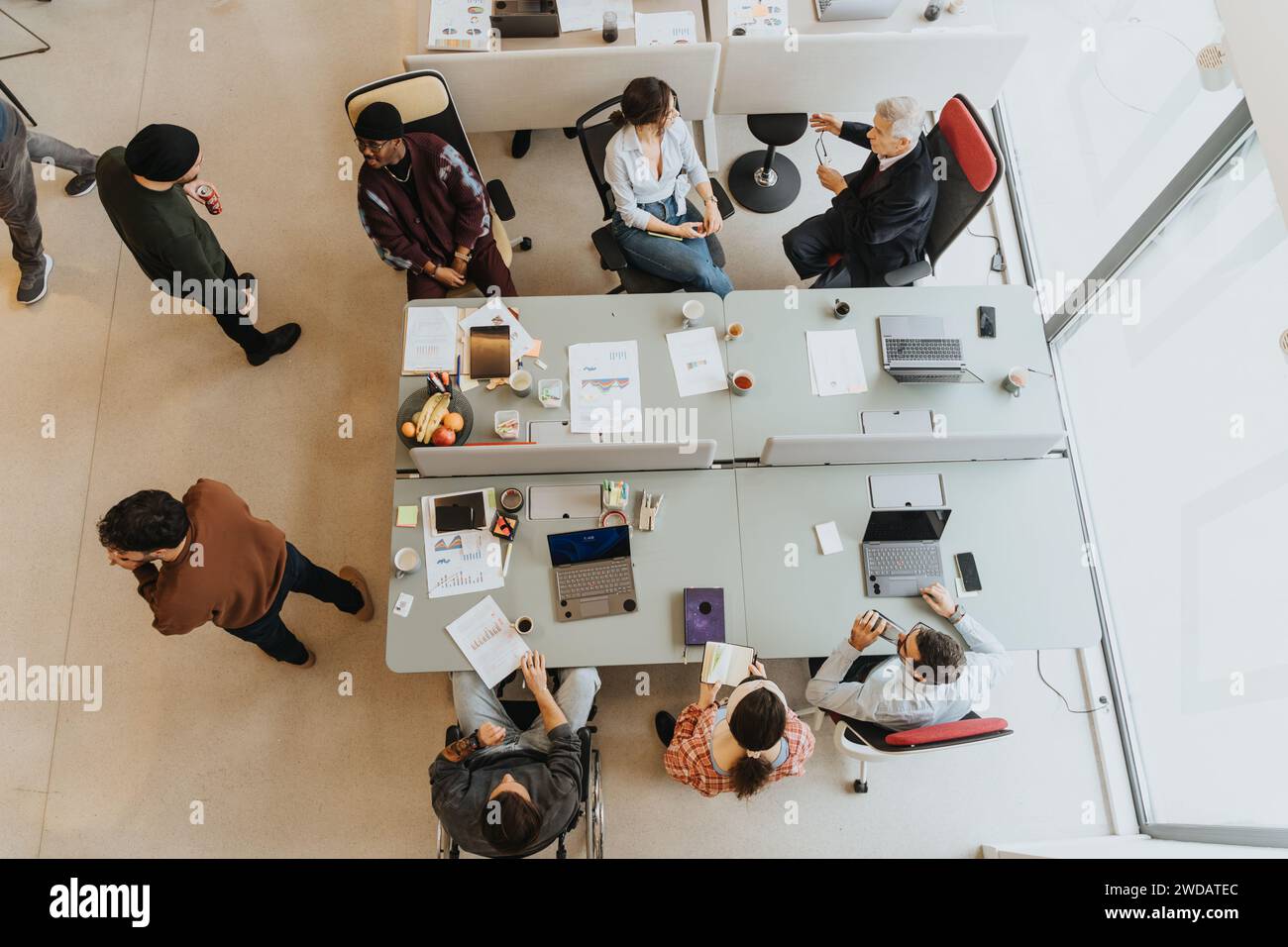 Kreative Büroumgebung mit vielfältigen Teams, die an Zusammenarbeit und Diskussion beteiligt sind. Foto von oben. Stockfoto