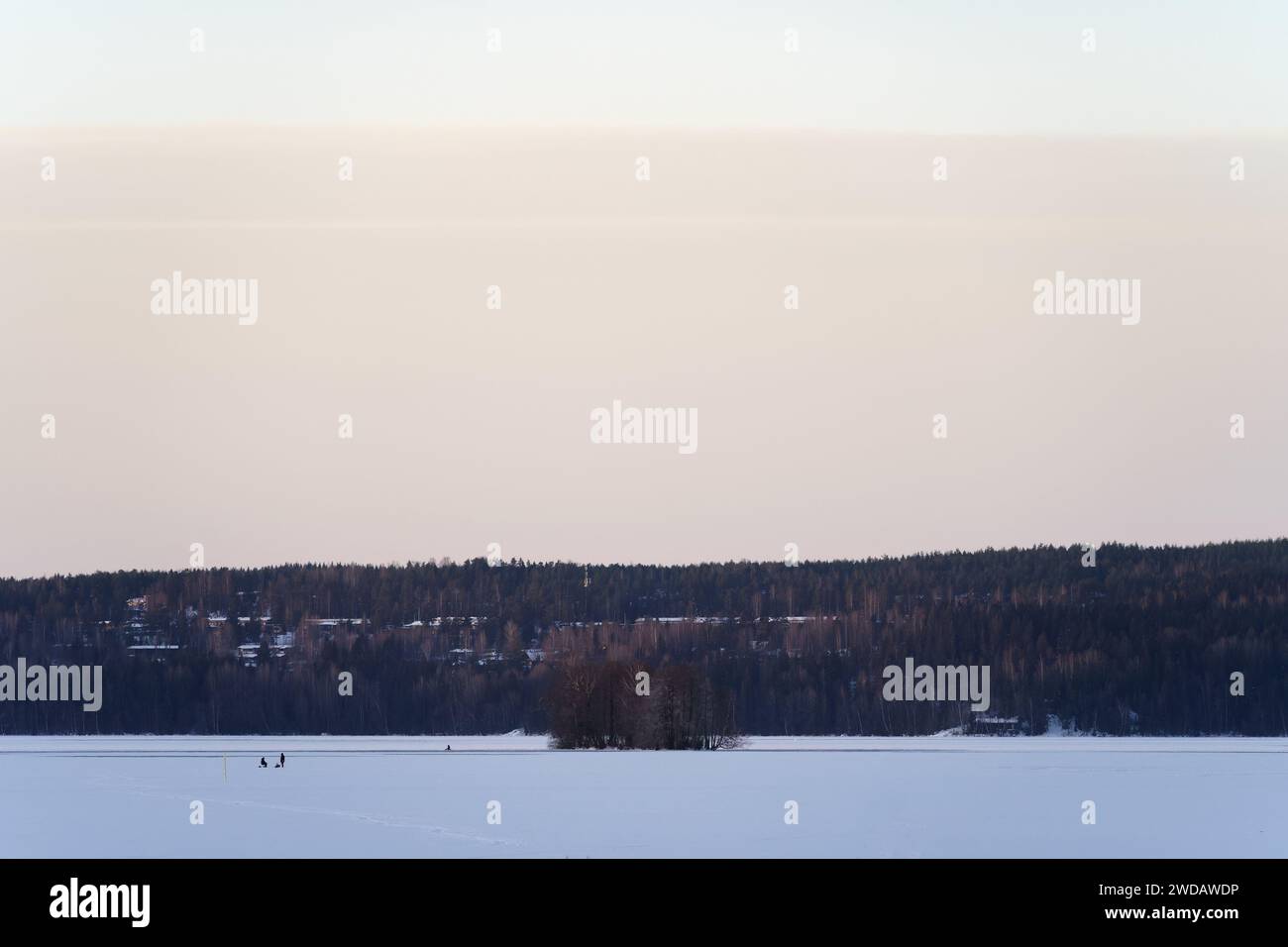 Gefrorene Seenlandschaft mit Leuten, die Eisfischen in der Ferne. Lahti, Finnland. Stockfoto