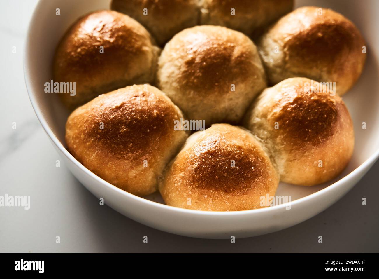 Burger-Brötchen oder Mini-Brötchen in der runden Backform. Sehr weich, frisch gebacken, hausgemacht, gebuttert. Weißer Marmorhintergrund. Minimalistisches Foto Stockfoto