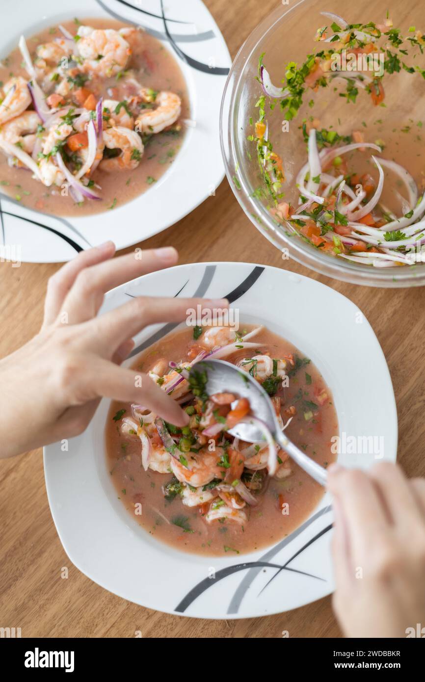 Zubereitung und Dekoration von Shrimps Ceviche, traditionelles Essen aus Ecuador, Studio Foto als Tapete, gesunde Suppe, appetitliche Menü Stockfoto