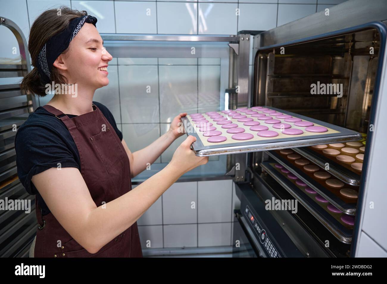 Der fröhliche junge Bäcker backt Kekse in der Bäckereiküche Stockfoto
