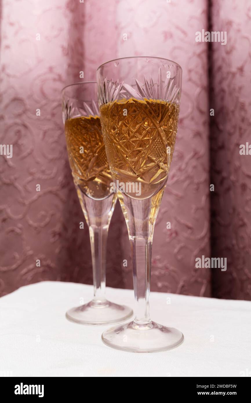 Zwei Kristallgläser mit Champagner auf einem Vorhang, Konzept im Stil der 90er Jahre Stockfoto