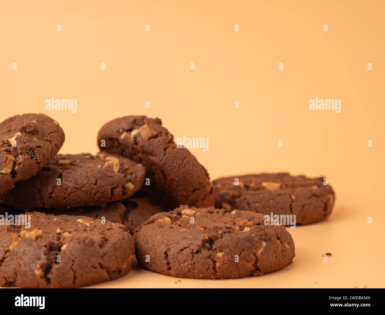 Schokoladige, reichhaltige Kekse mit kontrastierenden weißen Schokoladenchips auf orangem Hintergrund. Kekse mit weißer Schokolade in Nahaufnahme. Stockfoto