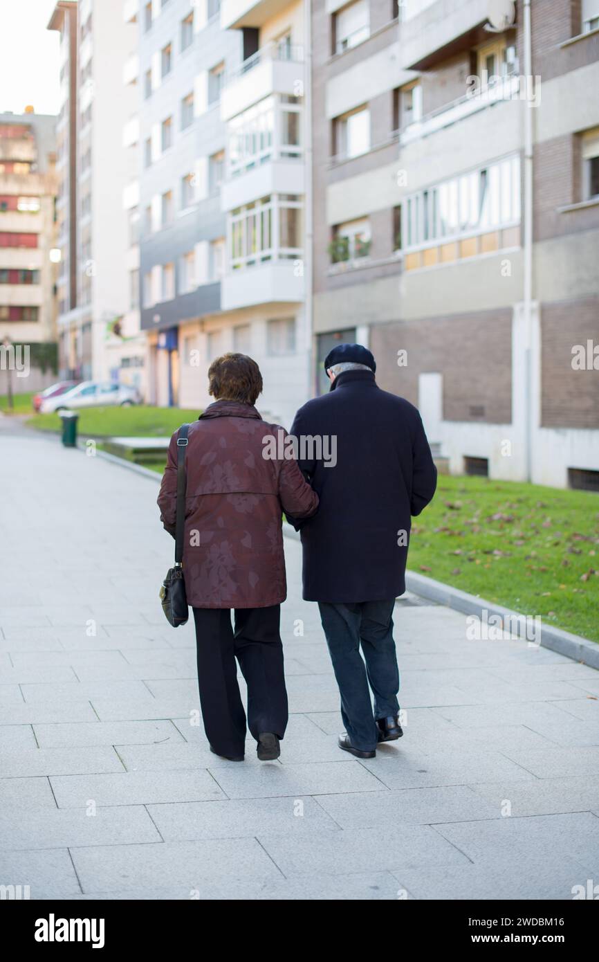 Ein Paar im Alter von over70 Jahren, das an einem sonnigen Tag von hinten auf einer leeren Straße unterwegs war. Konzept soziale Distanz covid 19 Stockfoto