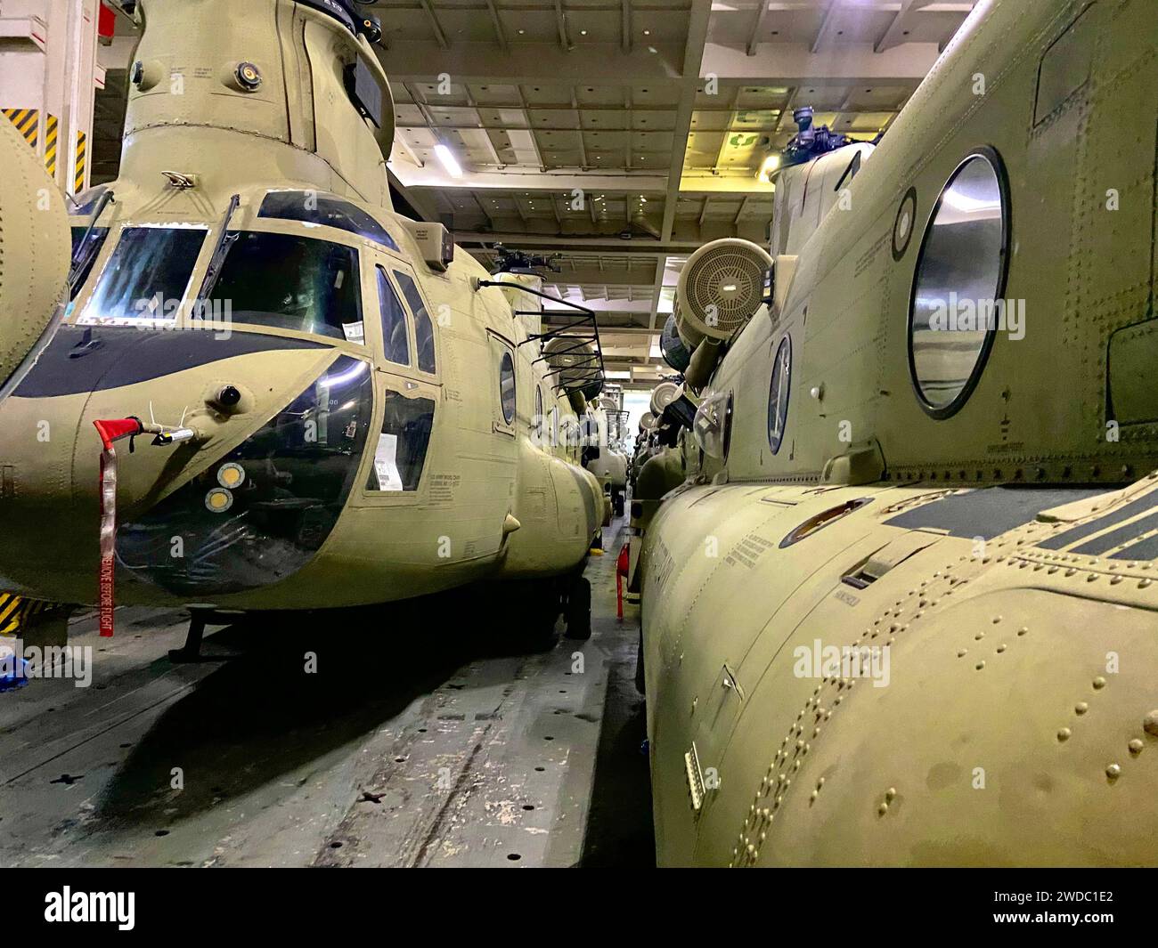 Gesicherte CH-47 Chinook Hubschrauber, die der 82nd Airborne Combat Aviation Brigade zugeteilt wurden, warten auf den Download vom Green Cove Frachtschiff an einem nicht bekanntgegebenen Ort im zentralen Einsatzgebiet der US Army 8. Dezember 2023. nach einem globalen Transport, der durch das Surface Deployment Distribution Command und Mitglieder der US-amerikanischen Handelsmarines erleichtert wurde. Der Hafenbetrieb ist von entscheidender Bedeutung, um einen nahtlosen logistischen Einsatz für eine nachhaltige Projektion der Kampftruppe zu gewährleisten. Diese Luftverkehrsmittel werden es den Soldaten ermöglichen, Truppen in der gesamten Region rasch mit Luftlieferungen zu unterstützen Stockfoto