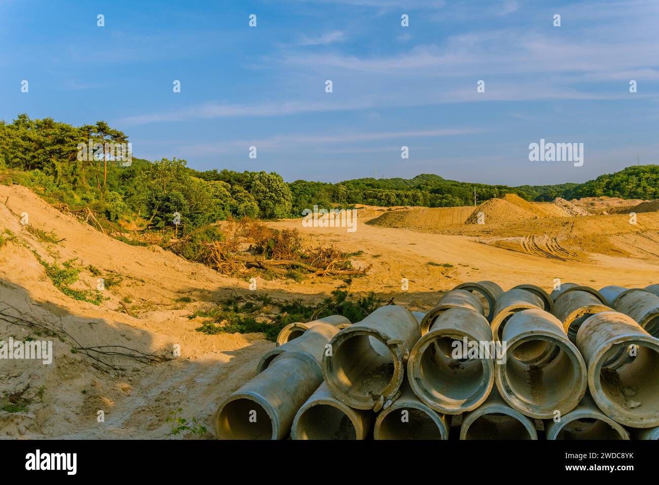 Landschaft aus Land, das für die Erschließung gerodet wurde, mit großen Betonabflussrohren, die im Vordergrund zusammengestapelt sind, Südkorea Stockfoto
