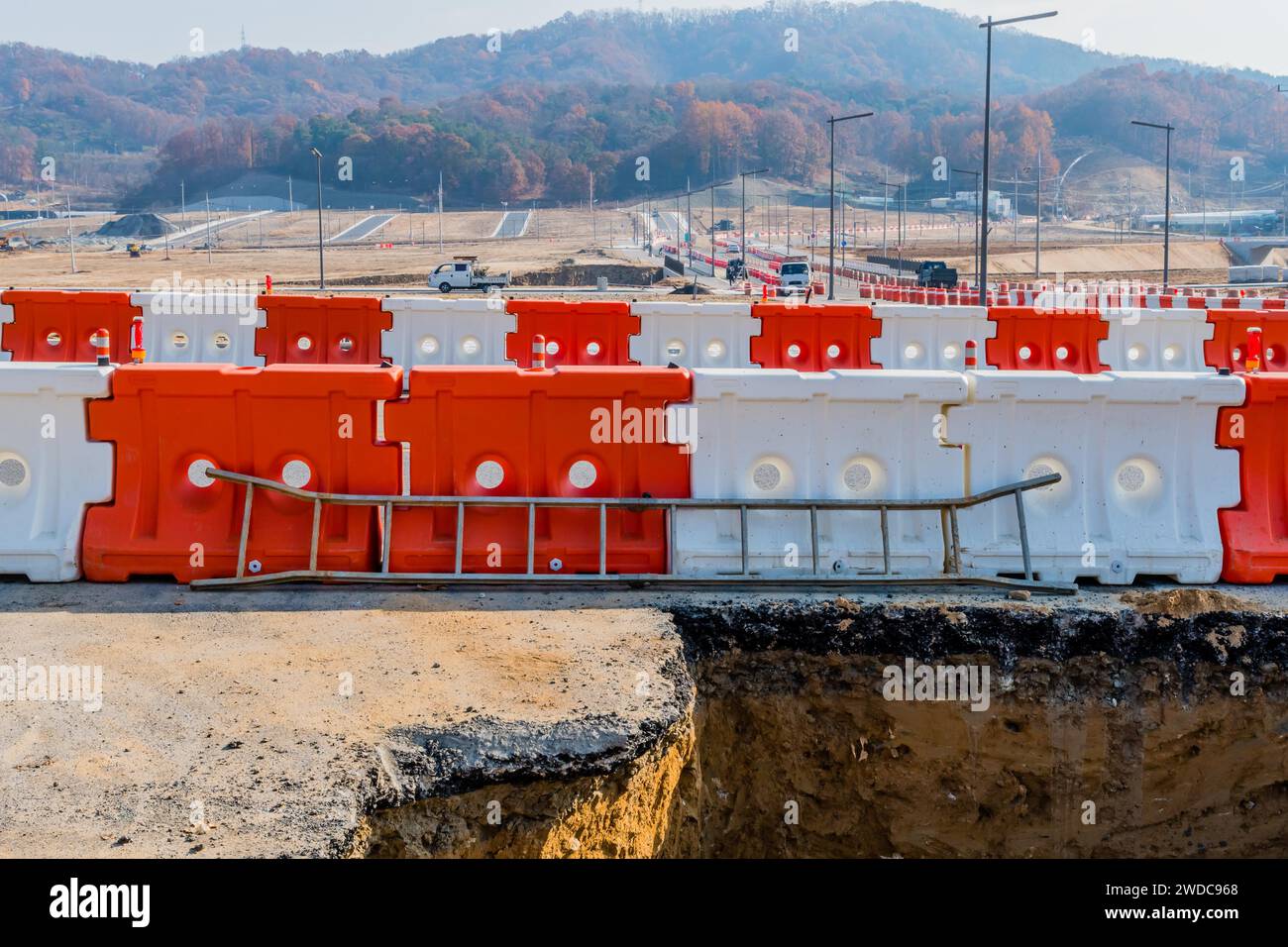 Leiter, die gegen Kunststoffbarrieren vor einem großen Loch im Boden auf einer neuen Wohnbaustelle in Südkorea, Südkorea, Südkorea, gelehnt ist Stockfoto