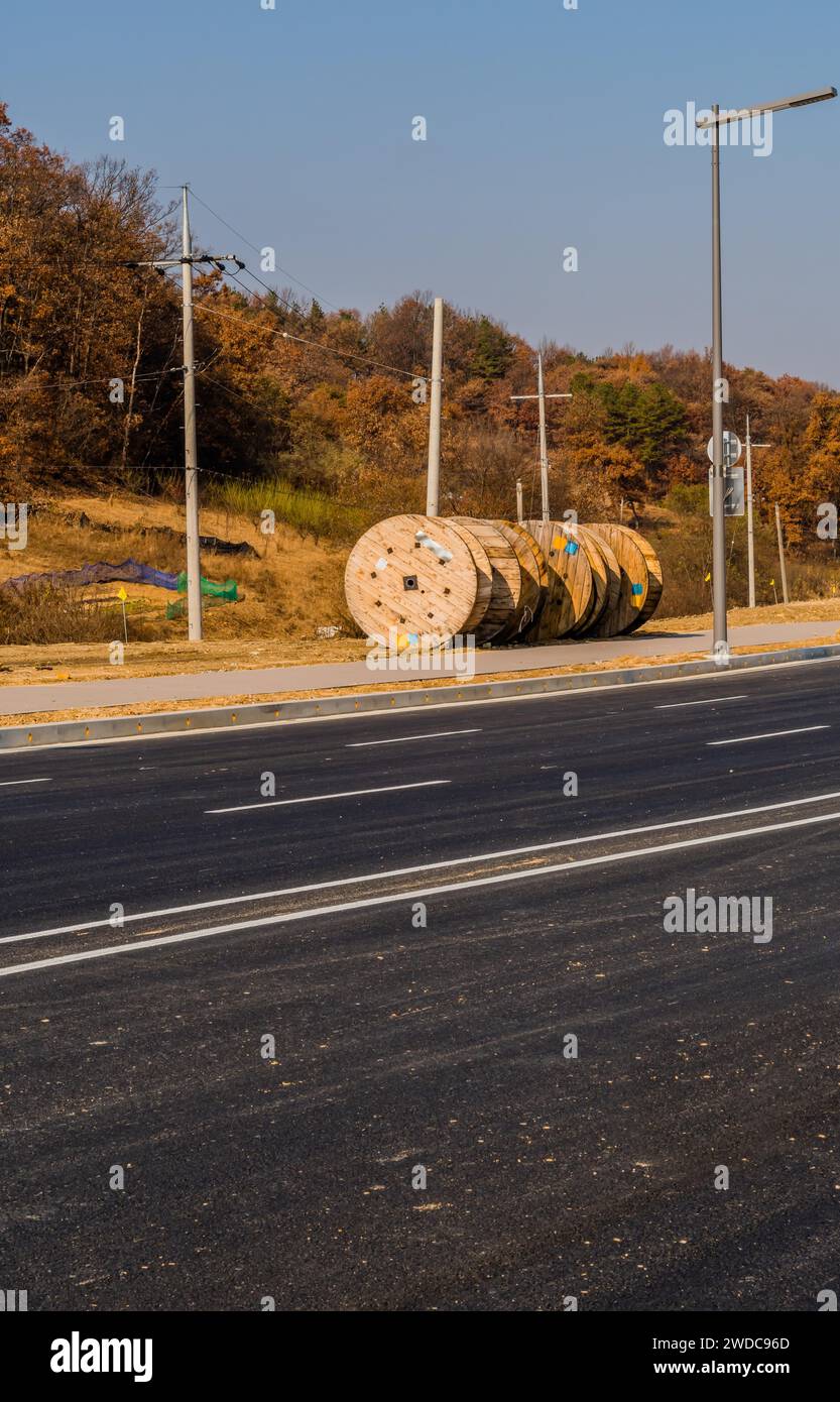 Große industrielle Holzspulen auf dem Boden neben dem Bürgersteig der asphaltierten Straße, Südkorea, Südkorea Stockfoto