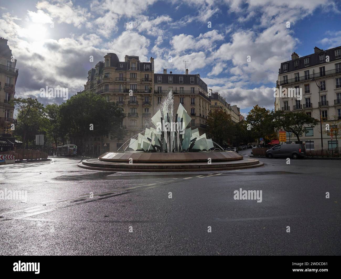 Ein Brunnen mit glasähnlichen Konstruktionen in der Mitte eines städtischen Platzes an einem teilweise bewölkten Tag, 20e Arrondissement Paris Stockfoto