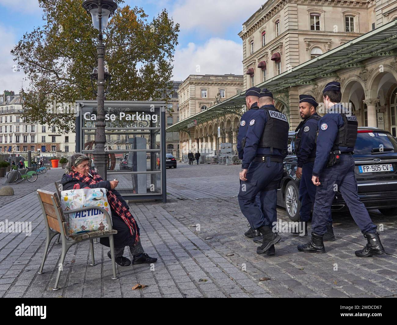 Polizisten gehen an einer sitzenden Person vorbei, dem Gare de l'Est. Paris Stockfoto