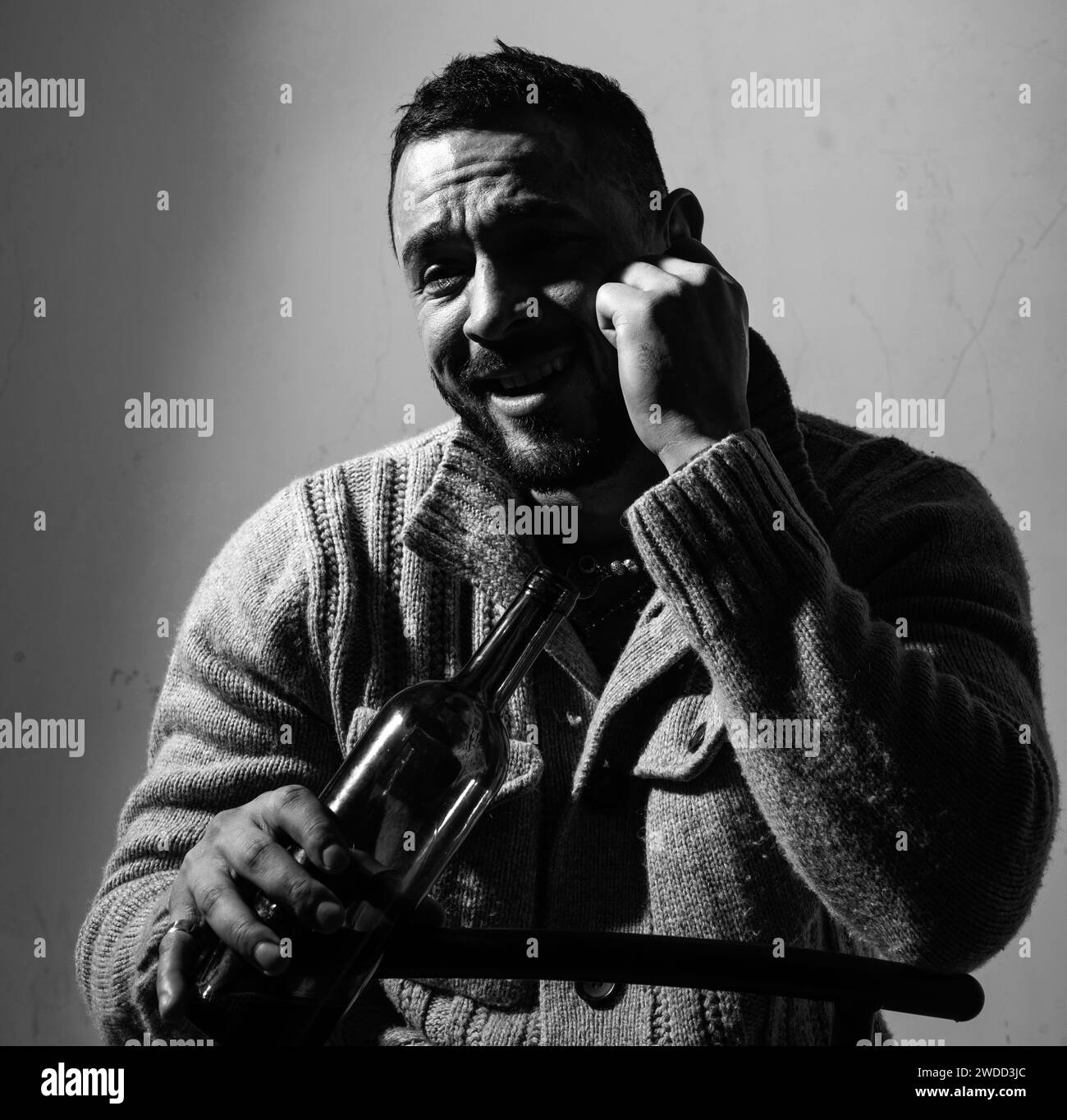 Betrunkener Mann, der Wein trinkt. Depressiver Kerl mit Flasche Alkohol, traurig und unglücklich. Stockfoto