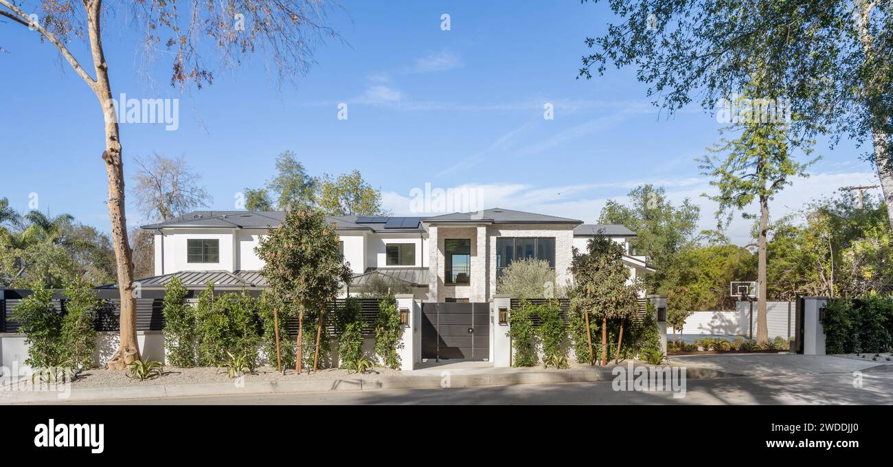 Ein bezauberndes weißes Haus liegt eingebettet zwischen üppigem Laub von Bäumen und Büschen an einer ruhigen Straße, New Construction Home in Tarzana, Kalifornien Stockfoto