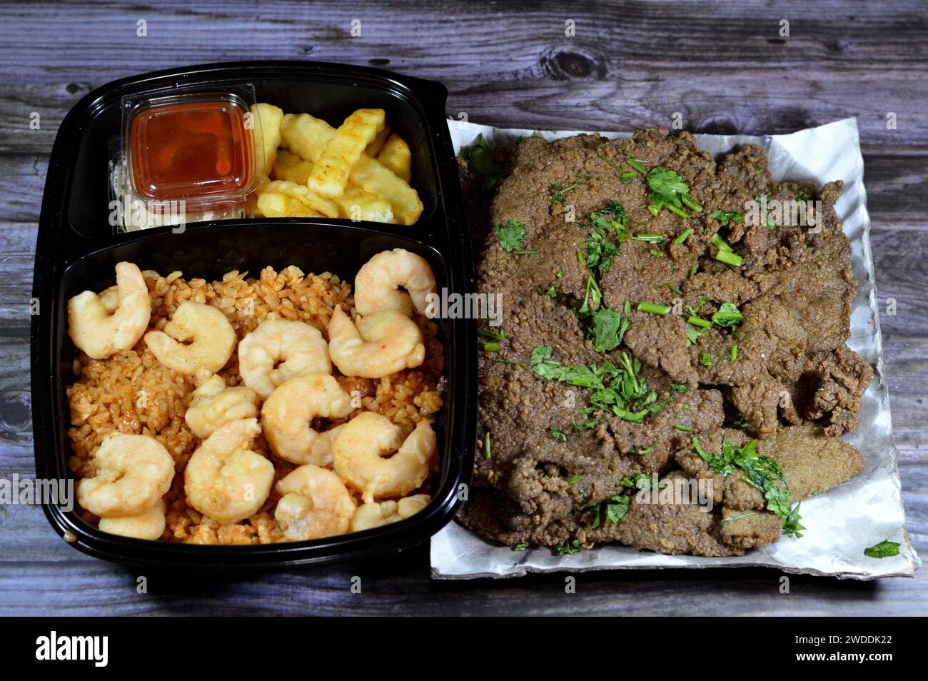 Gebratene Garnelen auf rotem Sayadieh-Reis, frittierte Pommes frites mit Tahini und Ketchup, Fischrezept mit Reisgarnelen, arabische frittierte Rindsleber sl Stockfoto