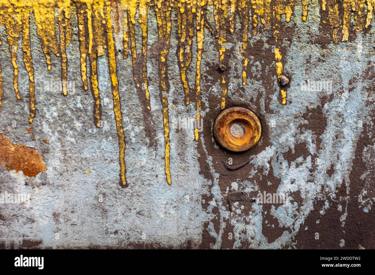 Eine verrostete Schraubenmutter auf einer verwitterten Metallplatte mit gelben Lackrissen Stockfoto