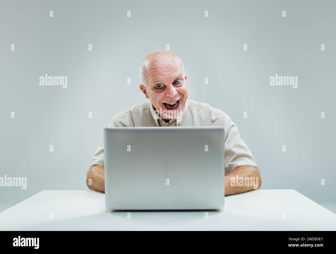 Der fröhliche Ausdruck des Mannes, während er auf den Laptop blickt, deutet darauf hin, dass er etwas herrlich verlockendes gefunden hat Stockfoto