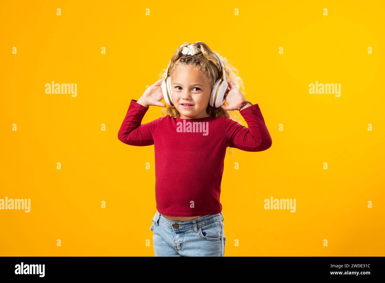 Fröhliches Kindermädchen mit Kopfhörern, in Musik verloren, ausdrucksvoll tanzen – bezauberndes Bild in einem Moment der reinen Freude. Stockfoto