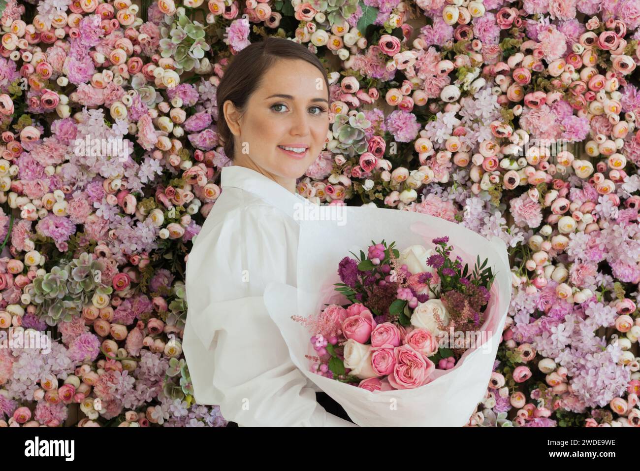 Glückliche gesunde Frau lächelt und hält bunte rosa Farbe Blumenstrauß auf floralem Frühling oder Sommer Hintergrund, Studio Mode Schönheit Porträt Stockfoto