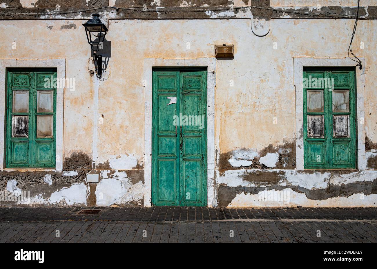 Zerbröckelnde, verrottete, weiß getünchte Wände mit den typischen grünen Türen und Fenstern. Stockfoto