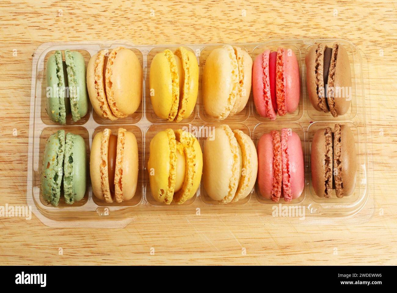 Auswahl an Macarons in einem Tablett auf einem Holzbrett, Draufsicht Stockfoto