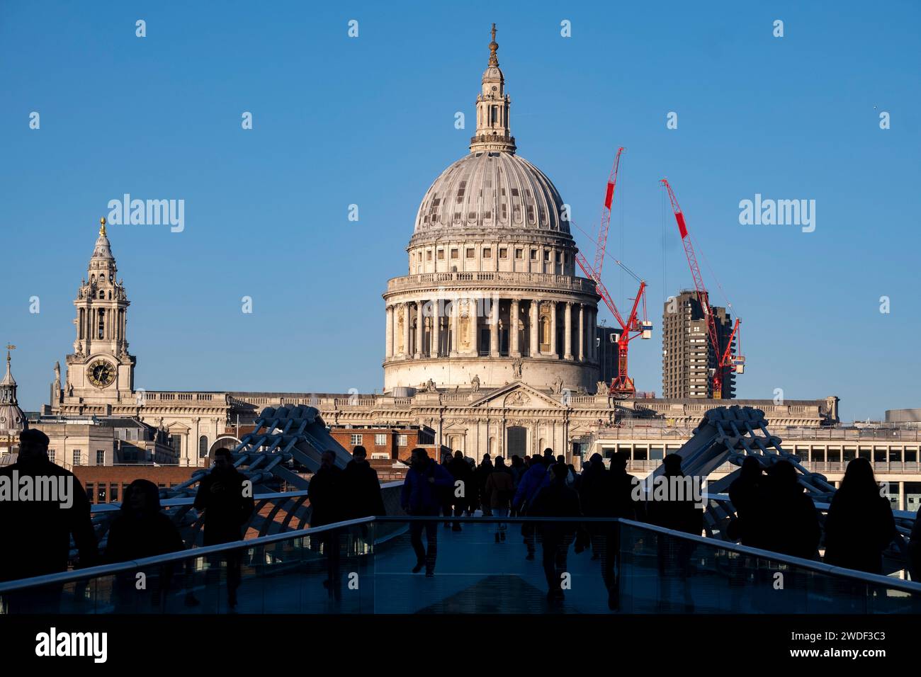 Blick auf Touristen und Einheimische, die am 16. Januar 2024 in London, Großbritannien, die Millennium Bridge überqueren, mit der St. Pauls Cathedral im Hintergrund. Die Londoner nannten die Brücke Wobbly Bridge, nachdem die Menschen in den ersten zwei Tagen nach der Eröffnung der Brücke eine unerwartete Schwingbewegung spürten. Stockfoto