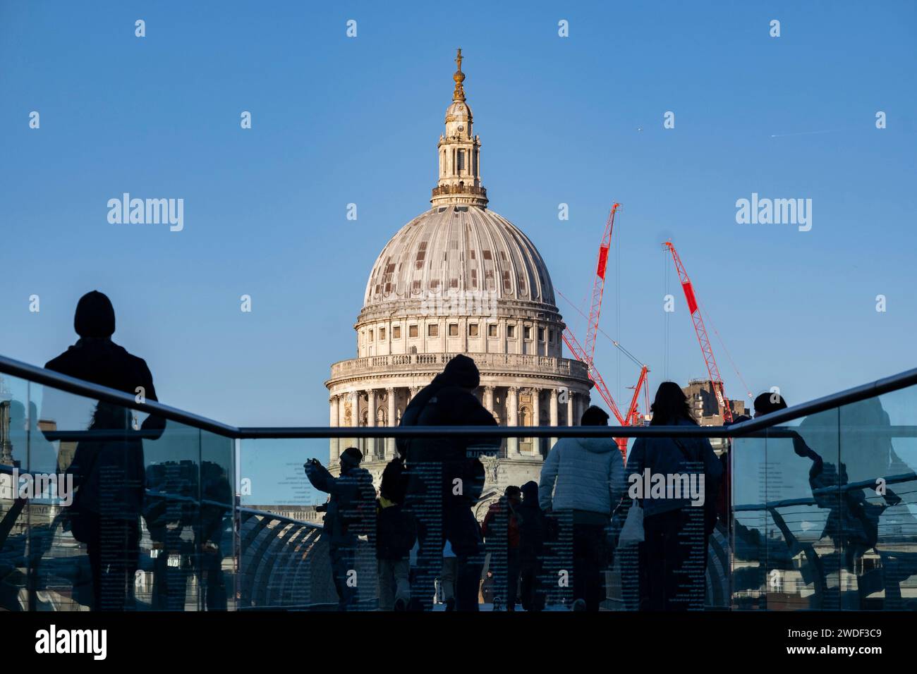 Blick auf Touristen und Einheimische, die am 16. Januar 2024 in London, Großbritannien, die Millennium Bridge überqueren, mit der St. Pauls Cathedral im Hintergrund. Die Londoner nannten die Brücke Wobbly Bridge, nachdem die Menschen in den ersten zwei Tagen nach der Eröffnung der Brücke eine unerwartete Schwingbewegung spürten. Stockfoto