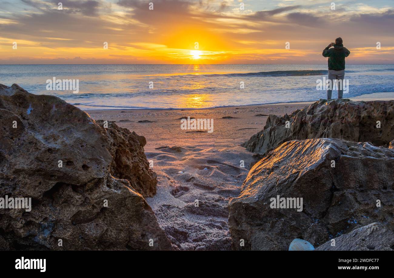 Fotograf, der einen atemberaubenden Sonnenaufgang am Strand festnimmt, ideal für Artikel auf Reisen, Fotografie-Workshops und Outdoor-Abenteuer. Stockfoto
