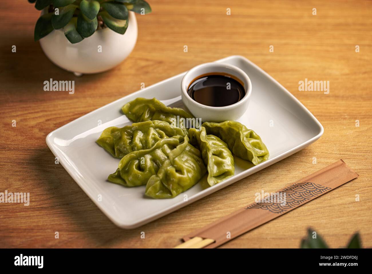Platte mit gedämpftem chinesischen Spinat, gefüllt mit Knödeln, serviert mit Sojasoße Stockfoto