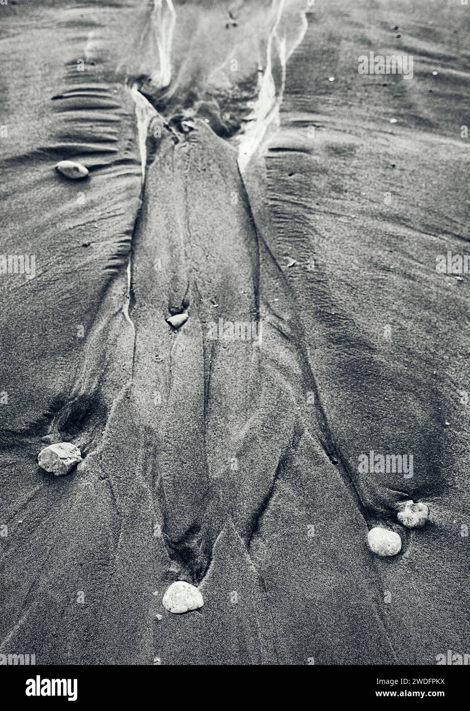 Rillen, die von Steinen im Sand während der Flut am Strand von Denia hinterlassen wurden Stockfoto