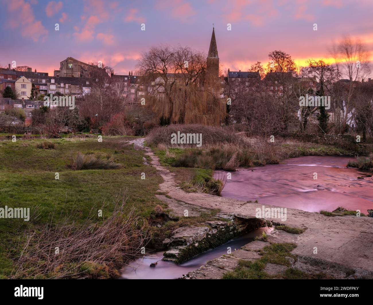 Samstag, 20. Januar 2024. Malmesbury, Wiltshire, England – wenn die Sonne über der gefrorenen Wasserwiese und der alten Klatschbrücke aufgeht, dreht sich der Himmel Stockfoto
