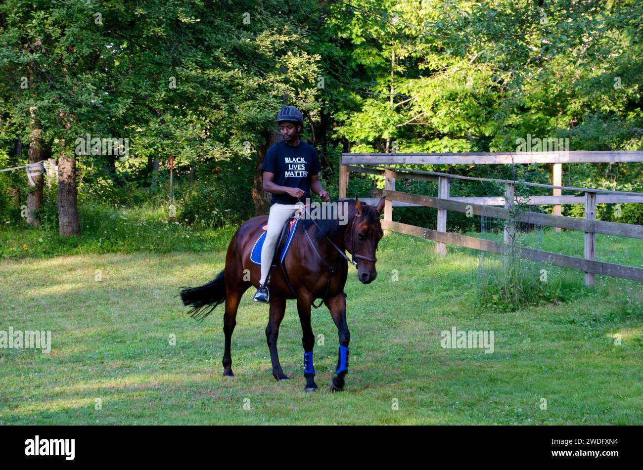 Der junge Afrikaner, Abdi Iftin, reitet an einem Sommerabend auf einem Quarterpferd in Maine, USA Stockfoto