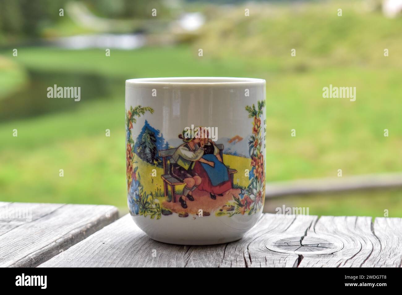 Tasse mit alpinem Motiv eines verliebten Paares in alpenländischer Tracht, auf einem Holztisch auf der Harmeralm am Schwarzensee, Kleinsoelktal Stockfoto