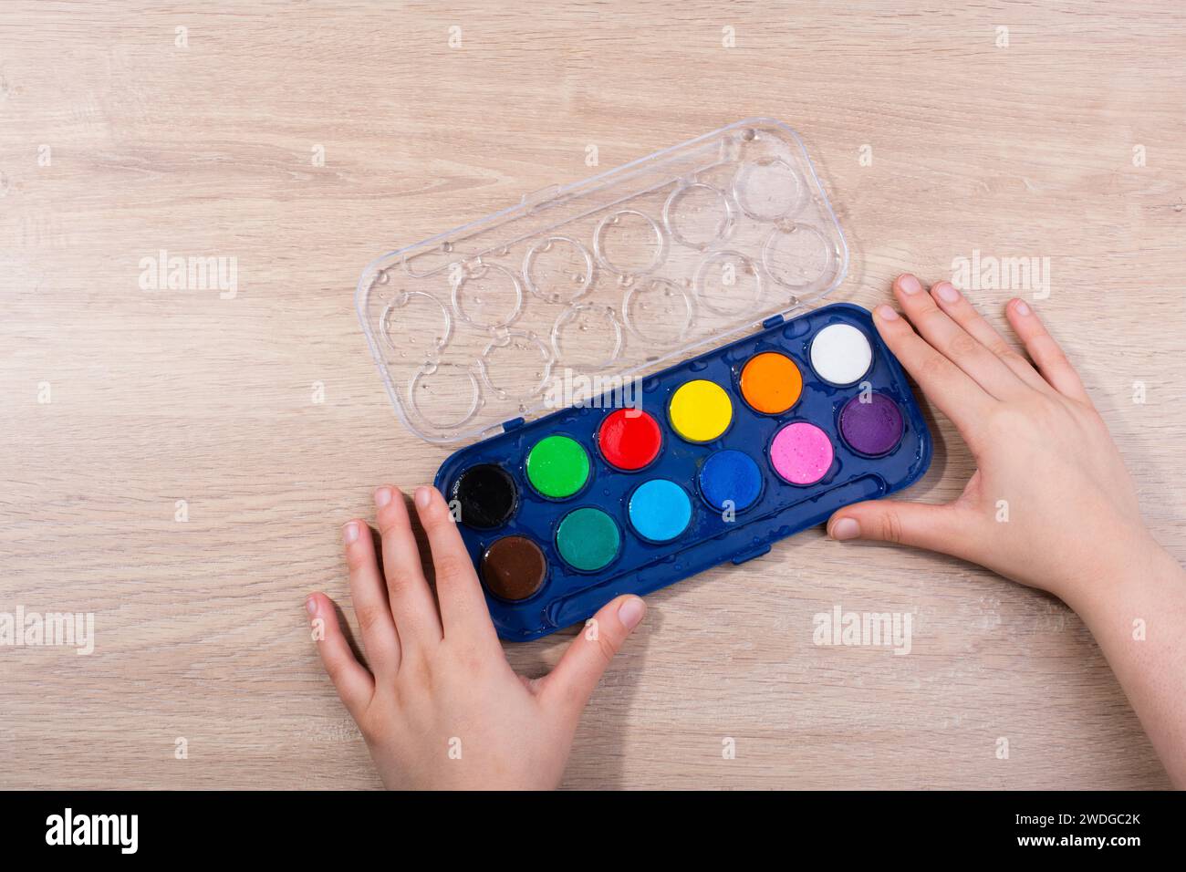 Hand mit einem Aquarell Paint Box auf einem hölzernen Hintergrund Stockfoto