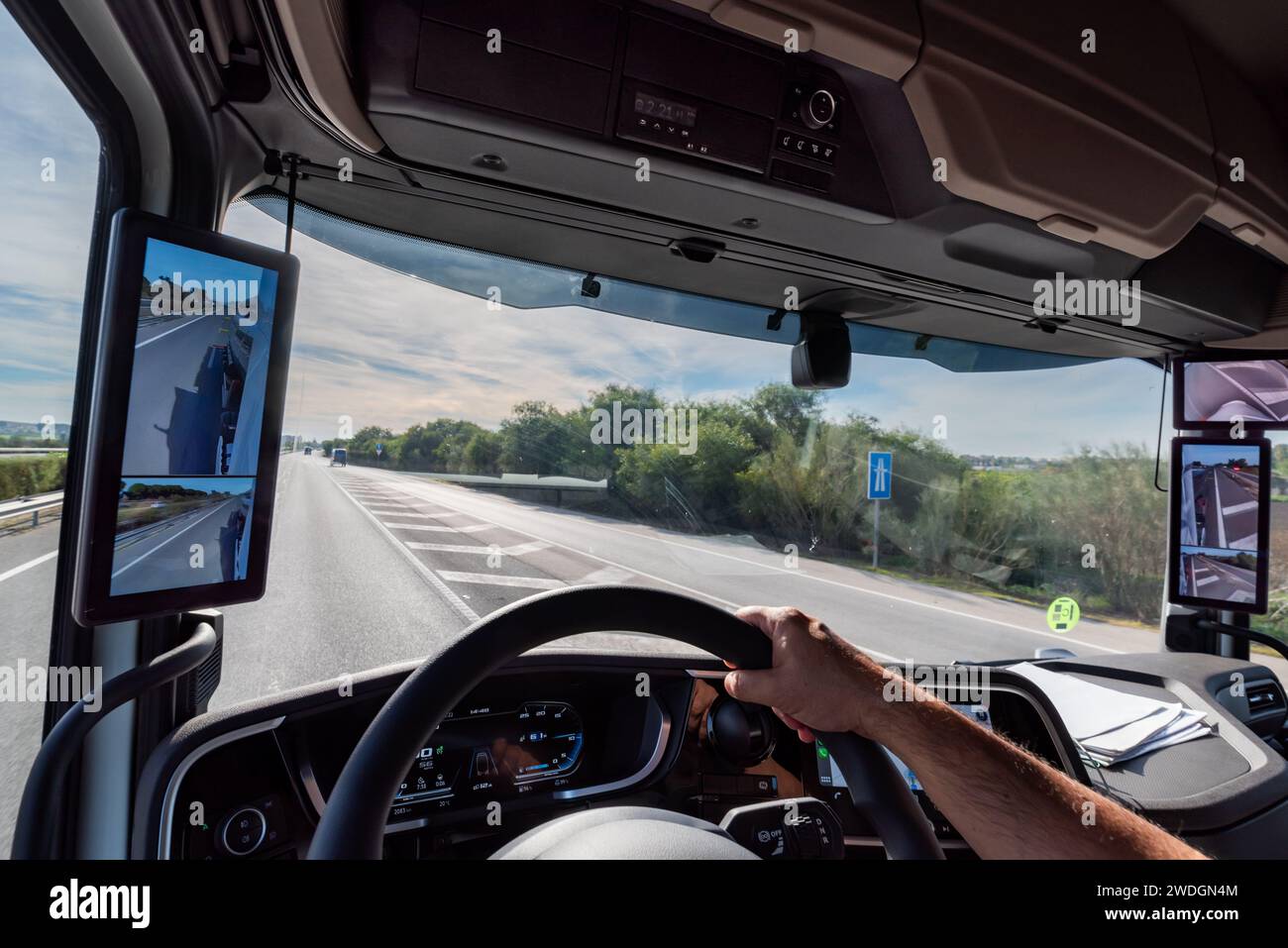 Sicht vom Fahrerplatz eines Lkw auf der Straße auf den Innenraum der Kabine mit den Bildschirmen als Rückspiegel. Stockfoto