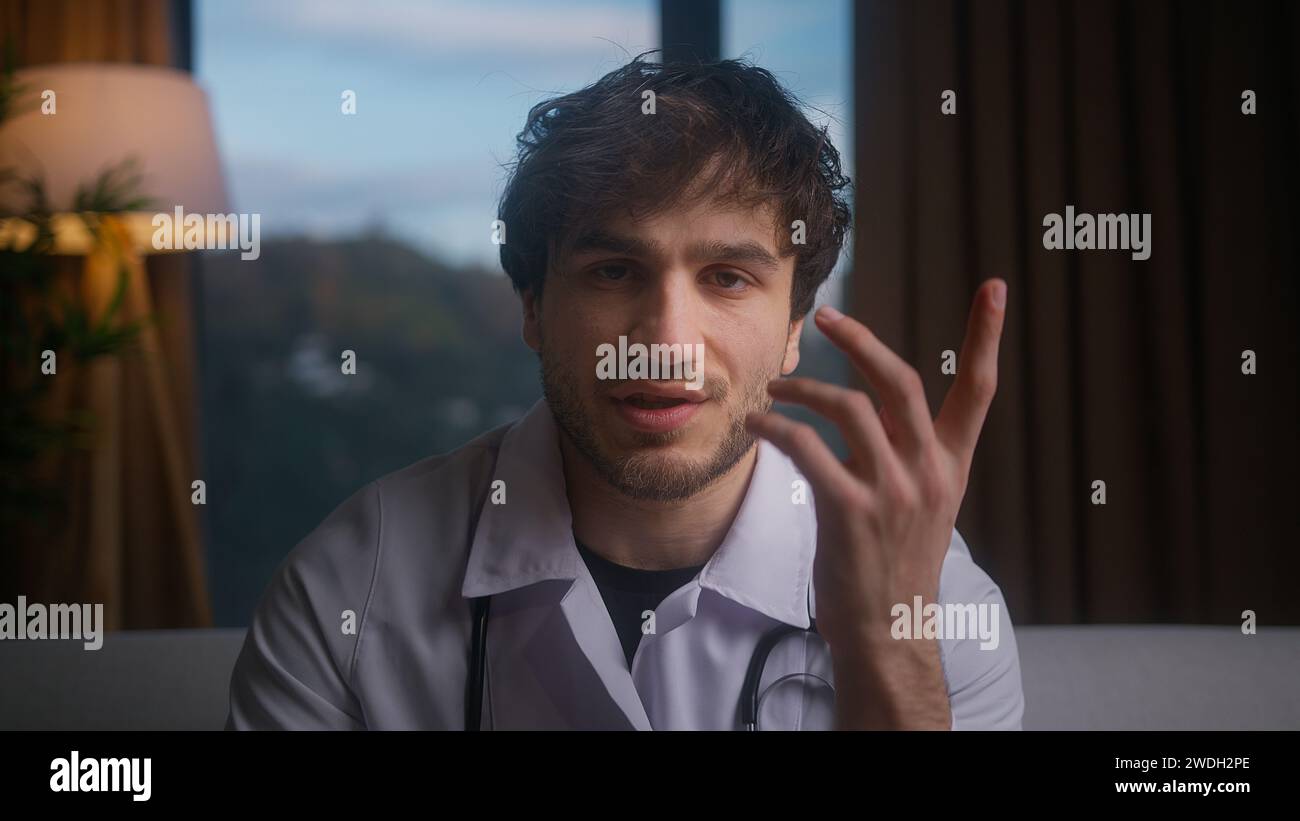 Ein professioneller männlicher Arzt trägt weiße Uniform mit Stethoskop, der Videokonferenzen führt, online mit dem Patienten chatten und die Kamera in die Webcam schaut. Rem Stockfoto