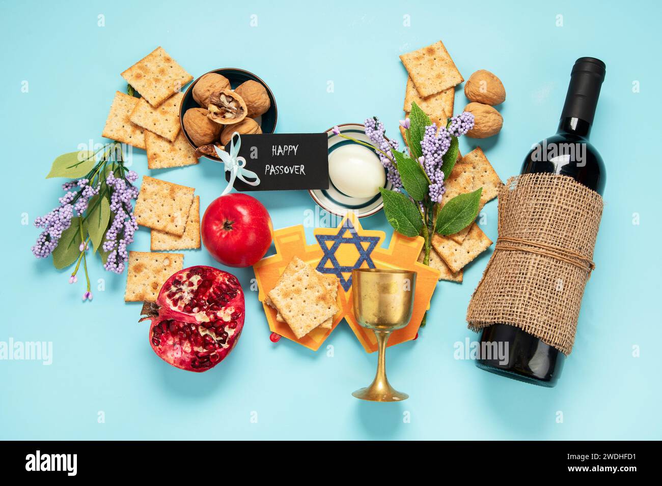 Passover-Feier-Konzept. Matzah, roter koscherer Nussbaum und schöne Frühlingsblumen auf blauem Hintergrund. Traditionelles rituelles jüdisches Brot. Stockfoto