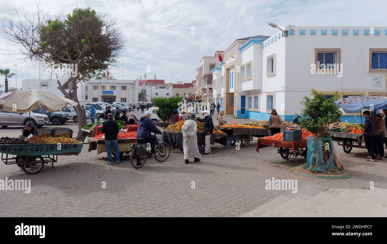 Menschen auf einem Obst- und Gemüsemarkt im Freien mit Parkplatz dahinter in Essaouira, Marokko, 20. Januar 2024 Stockfoto