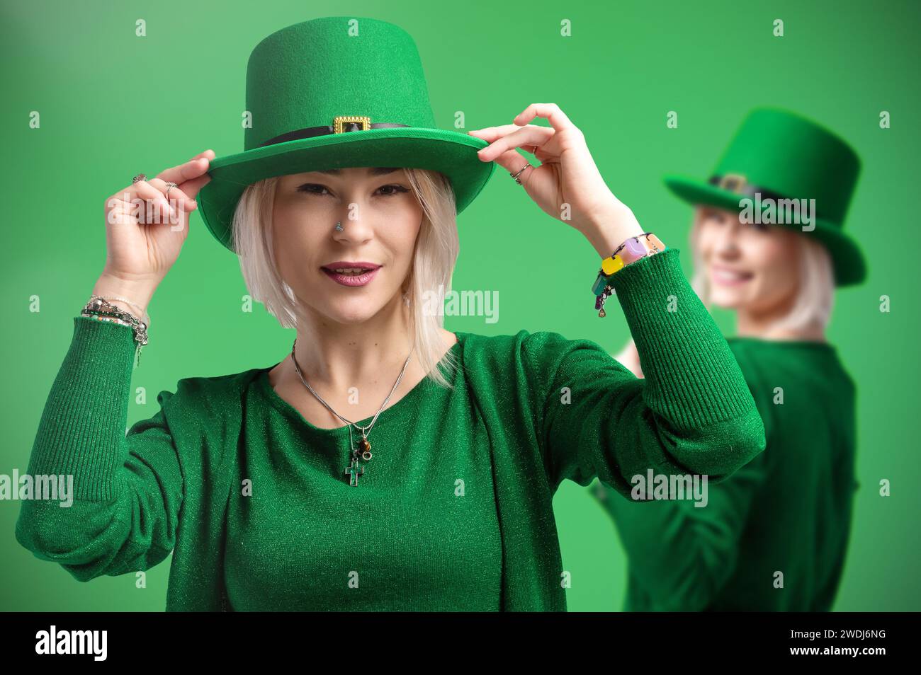 St. Patrick's Day. Zwei Frauen in Kobold-Hüten feiern St. Patrick's Day. Verdoppeln Sie den festlichen Geist vor einer lebendigen grünen Kulisse Stockfoto