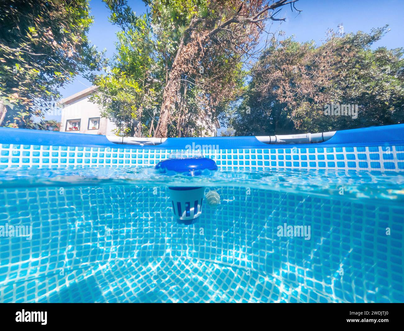 Geteilter Unterwasserblick auf einen Chlorwasserspender in einem privaten Swimmingpool Stockfoto