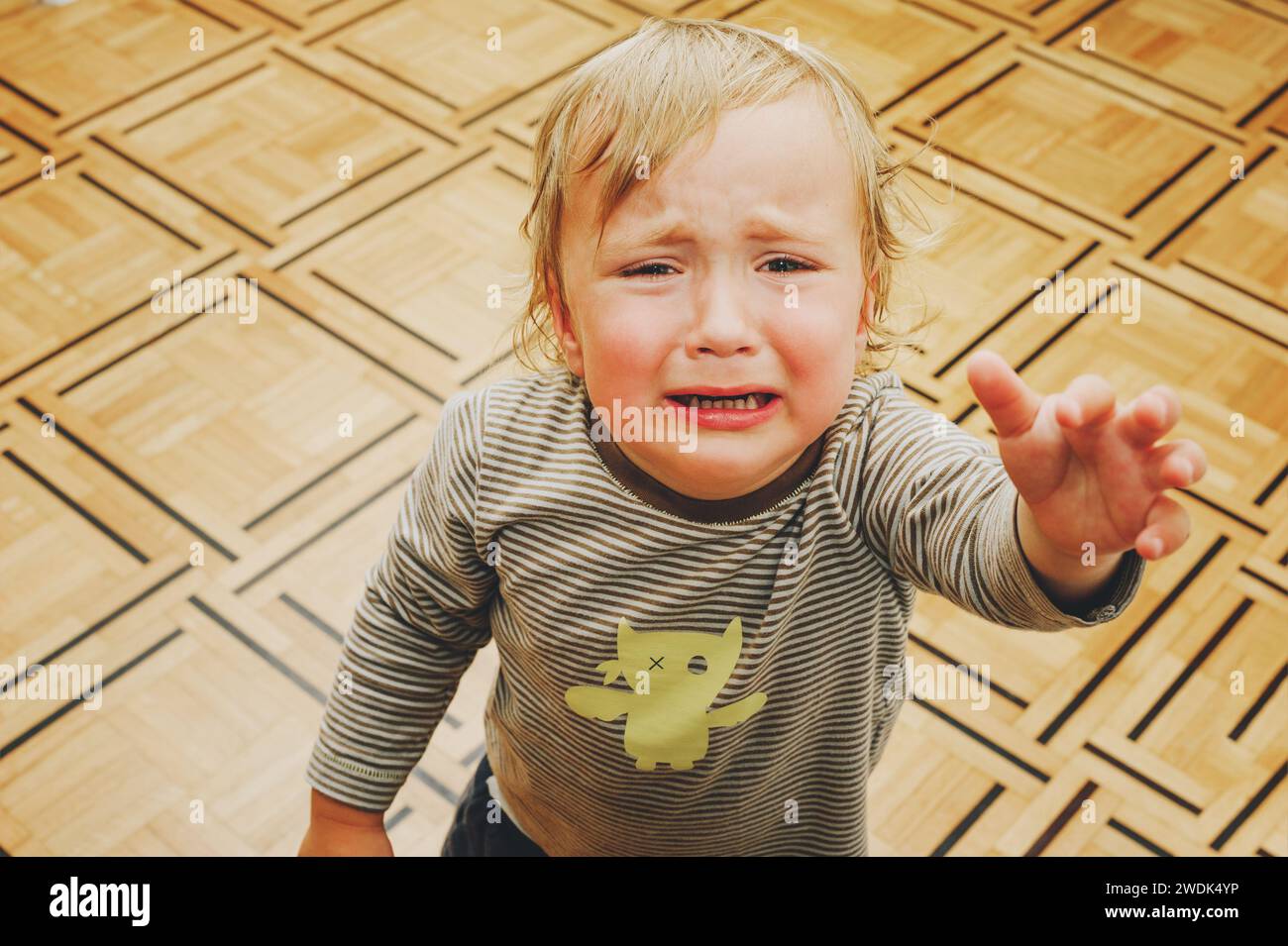 Porträt eines weinenden Kleinkindes, das die Hände zur Mutter zieht Stockfoto