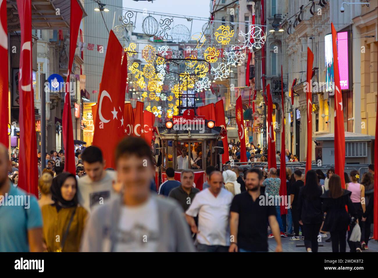 Türkische Fahnen mit nostalgischer Straßenbahn und Menschen in der Istiklal Avenue. Istanbul Turkiye - 10.28.2023 Stockfoto