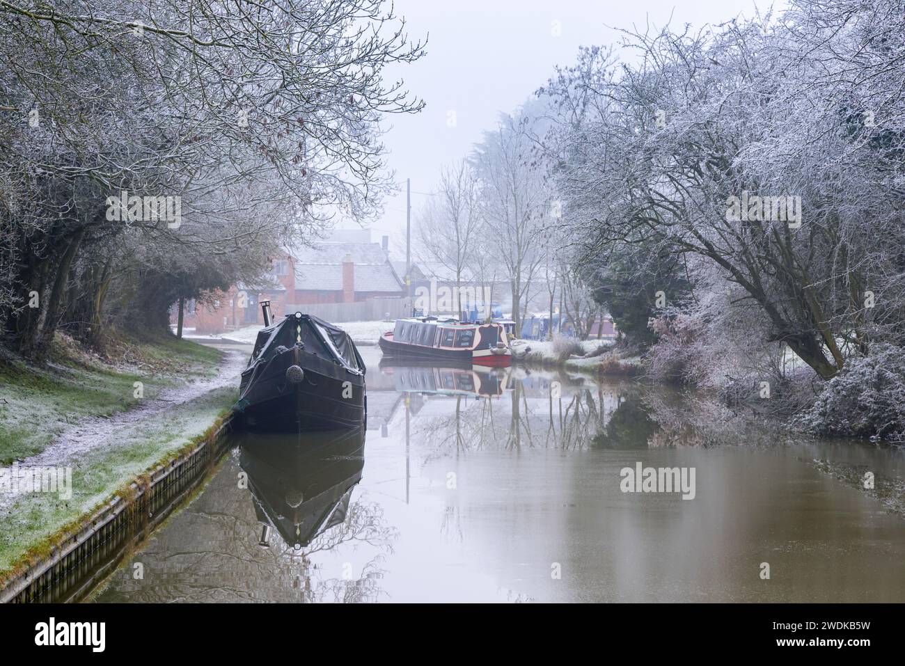 Crick, Northamptonshire – Januar 2021: An einem frostigen Morgen liegen zwei Schmalboote in Crick Wharf an einem teilweise gefrorenen Grand Union Canal. Stockfoto