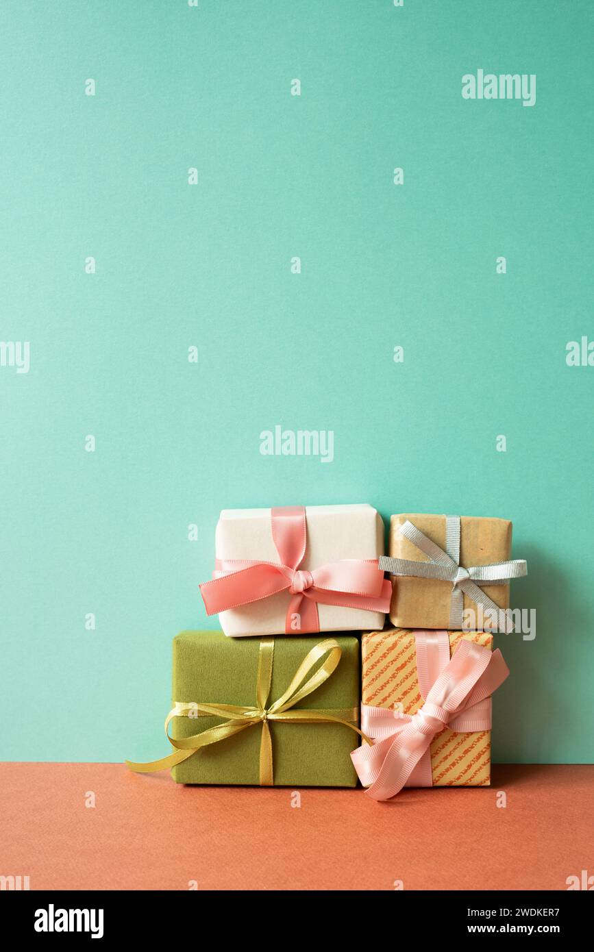 Bunte Geschenkbox auf rotem Tisch. Mintgrüner Wandhintergrund Stockfoto