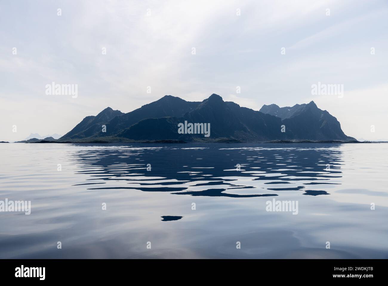 Ein ruhiges Panorama der Lofoten-Inseln mit glasklarem Wasser, das die zerklüfteten Gipfel unter einem weichen, diffusen Licht reflektiert Stockfoto